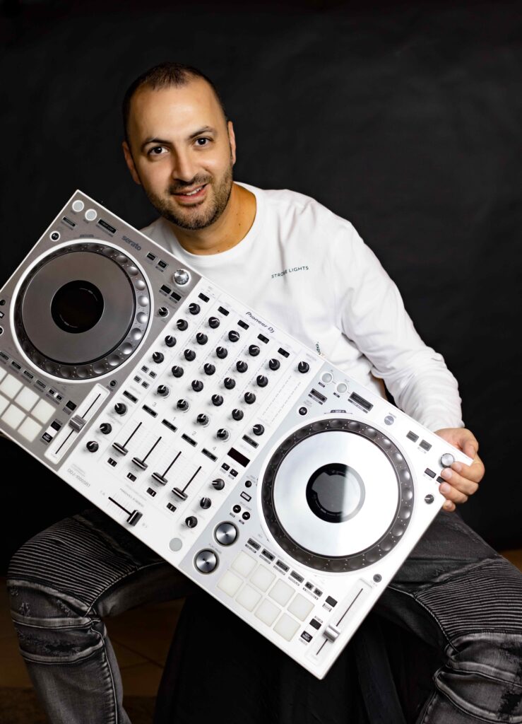 DJ Franky Flow holding a professional DJ controller, showcasing his expertise in blending Arabic and international music for high-energy events.